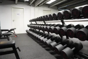 Kurzhantelbereich im Friendship Gym in Hamburg mit mehreren Hantelreihen und Trainingsbänken.