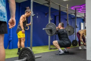 Trainer betreut Athlet bei einer Langhantelübung im Friendship Gym Hamburg.